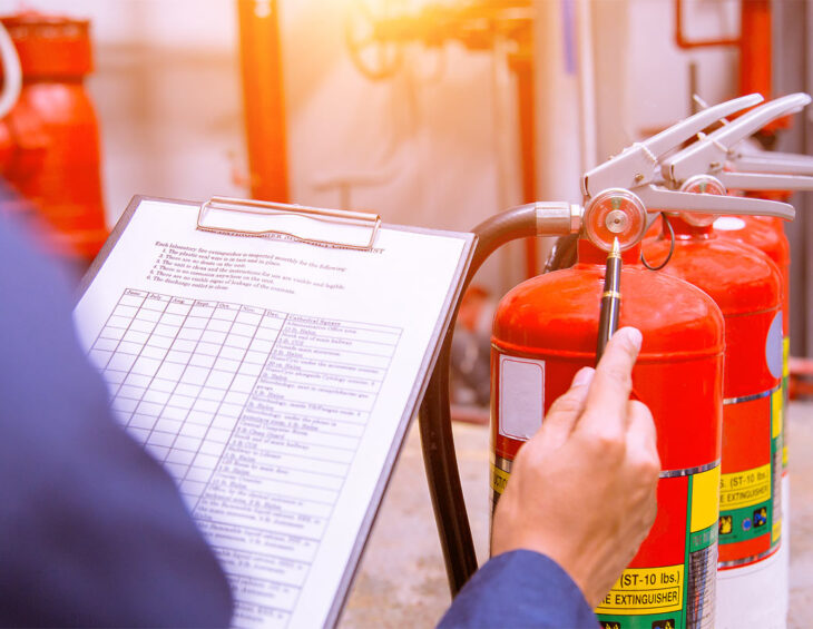 a person conducting a fire extinguisher inspection by checking the gauges