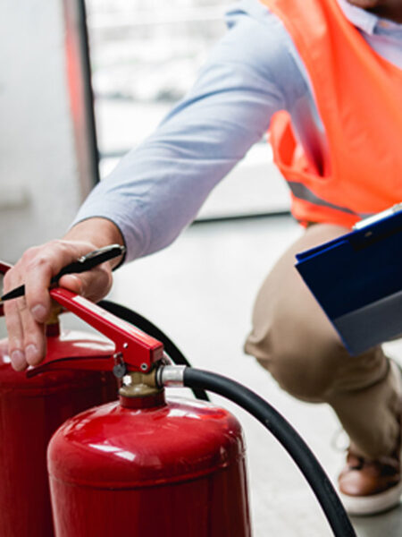 An inspector checking two fire extinguishers for exterior damages