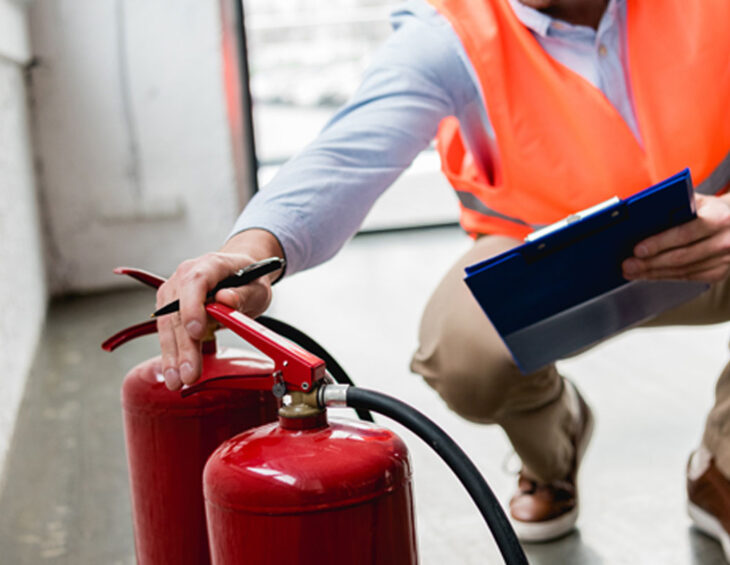 An inspector checking two fire extinguishers for exterior damages