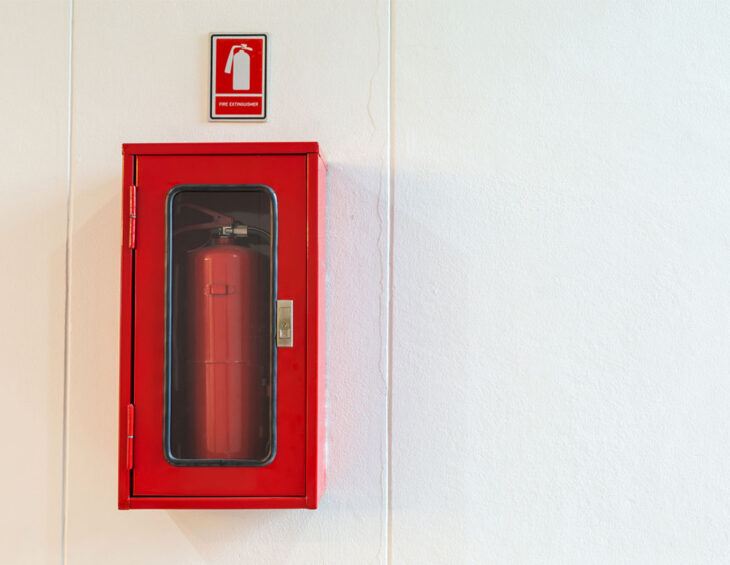 A fire extinguisher sitting in a mounted case on the wall